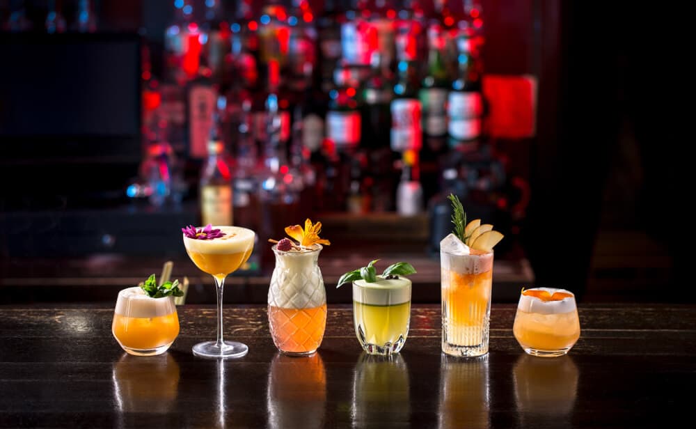 cocktails in a row with a nighclub background