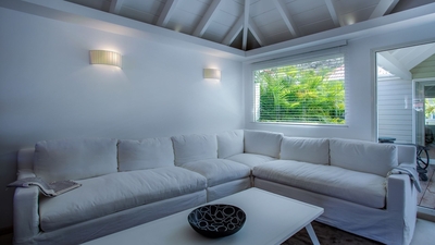 Living Area: Air-conditioned living room with a comfortable white sofa, a white table, and a flat sc